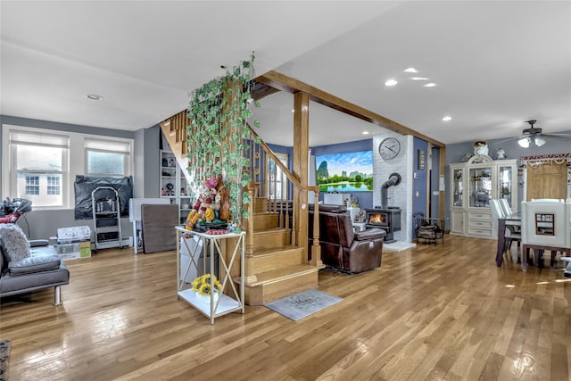 living area featuring recessed lighting, stairway, a wood stove, ceiling fan, and wood finished floors