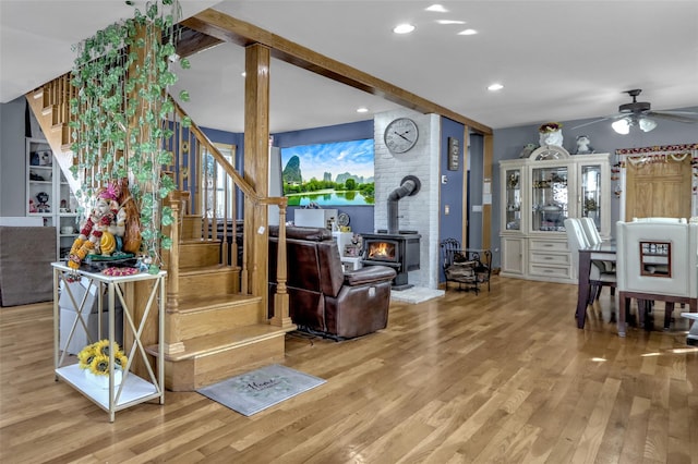 living area featuring ceiling fan, recessed lighting, wood finished floors, stairs, and a wood stove