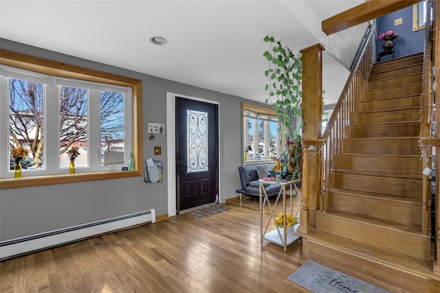 foyer with baseboards, stairs, a baseboard heating unit, and wood finished floors