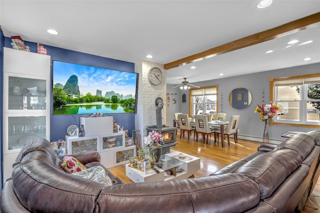 living area featuring beam ceiling, wood finished floors, a wood stove, and recessed lighting