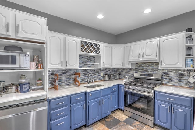 kitchen featuring blue cabinetry, appliances with stainless steel finishes, open shelves, and a sink