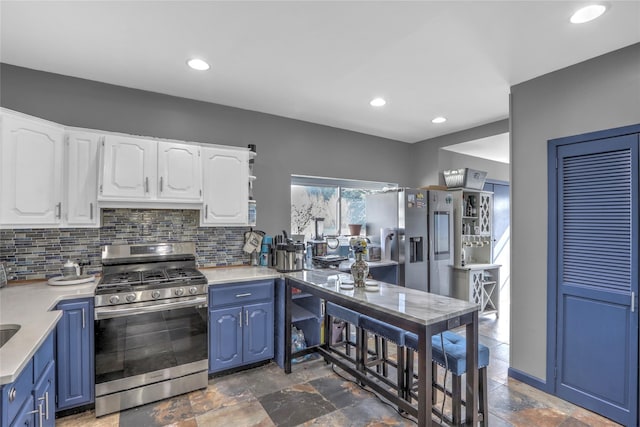 kitchen with blue cabinets, stone tile floors, appliances with stainless steel finishes, and white cabinets