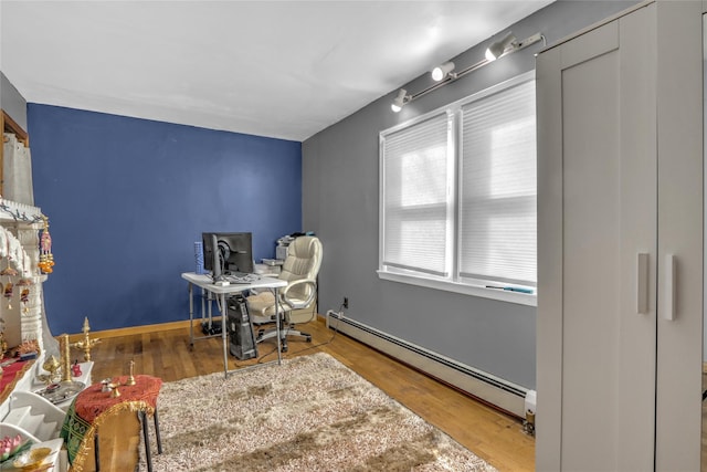 office space featuring a baseboard radiator, baseboards, and wood finished floors