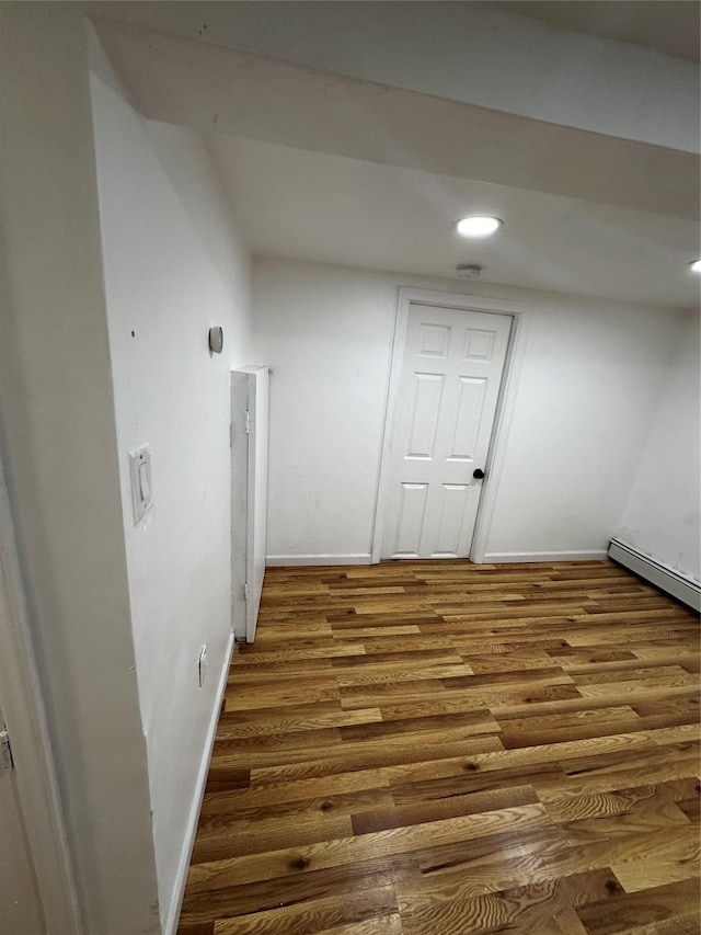 interior space with a baseboard heating unit, recessed lighting, baseboards, and wood finished floors