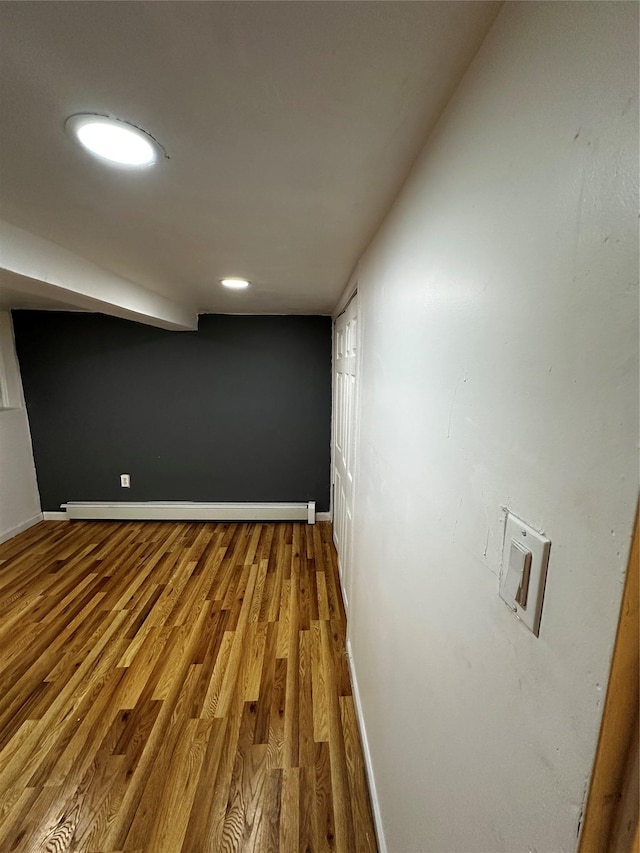 finished basement with baseboards, baseboard heating, and wood finished floors