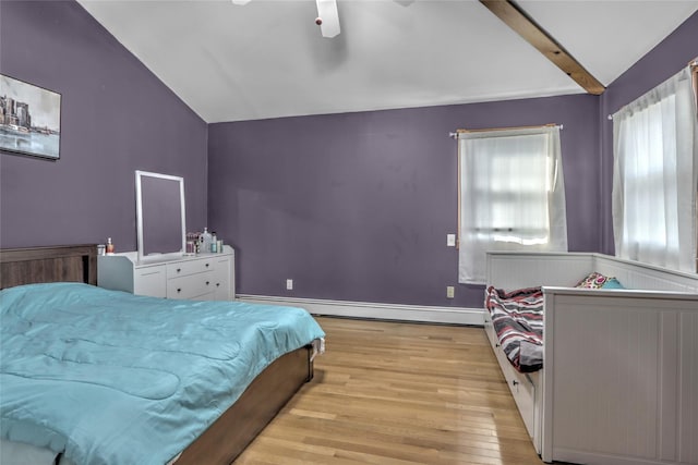 bedroom with lofted ceiling with beams, a baseboard heating unit, wood finished floors, and baseboards