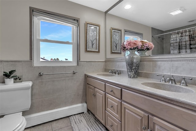 bathroom featuring a wealth of natural light, baseboard heating, a sink, and toilet