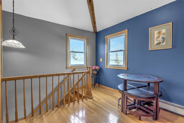 dining room featuring a baseboard heating unit, hardwood / wood-style floors, beamed ceiling, and baseboards