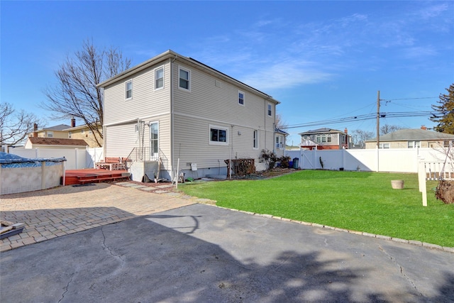 rear view of house with a yard, a fenced backyard, a fenced in pool, and a patio