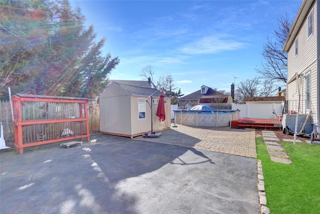 view of patio featuring a storage shed, fence, a fenced in pool, and an outdoor structure