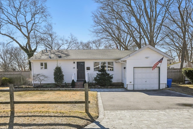 ranch-style home featuring a garage, a shingled roof, fence, and aphalt driveway