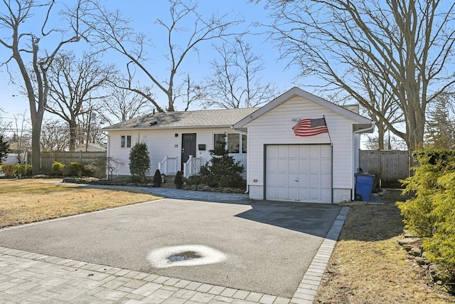 ranch-style house featuring a garage, fence, and aphalt driveway