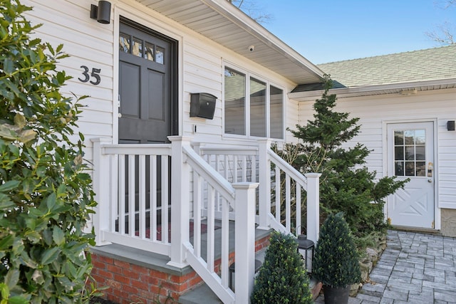 entrance to property featuring roof with shingles