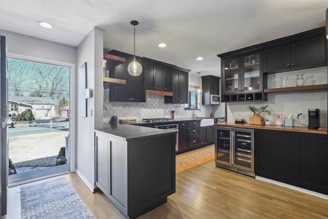 kitchen with dark cabinetry, light wood finished floors, and open shelves