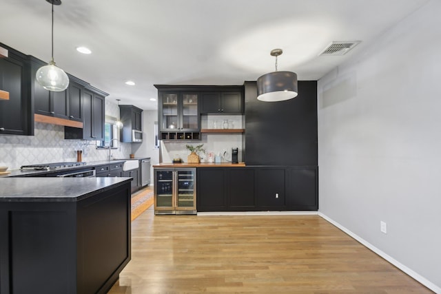 kitchen with beverage cooler, stainless steel appliances, visible vents, decorative backsplash, and light wood finished floors