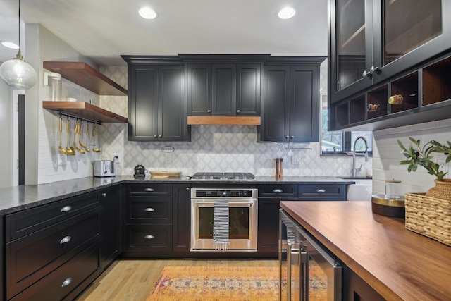 kitchen featuring stainless steel appliances, dark cabinets, wood counters, and open shelves