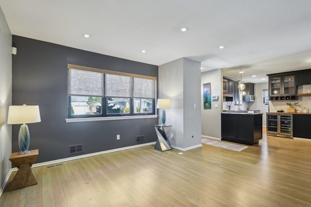 living area featuring light wood-type flooring, visible vents, and baseboards