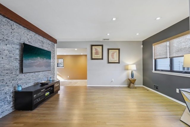 living area with light wood-style floors, visible vents, and a wealth of natural light