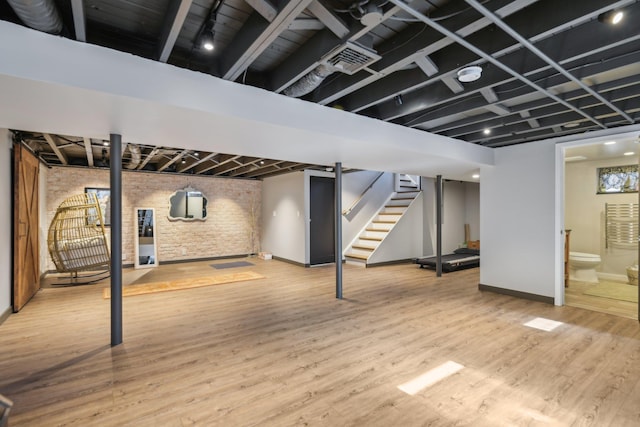 finished below grade area featuring visible vents, stairway, baseboards, and wood finished floors