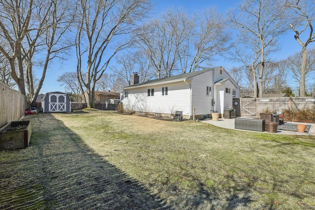 view of yard featuring a shed, a fenced backyard, and an outbuilding