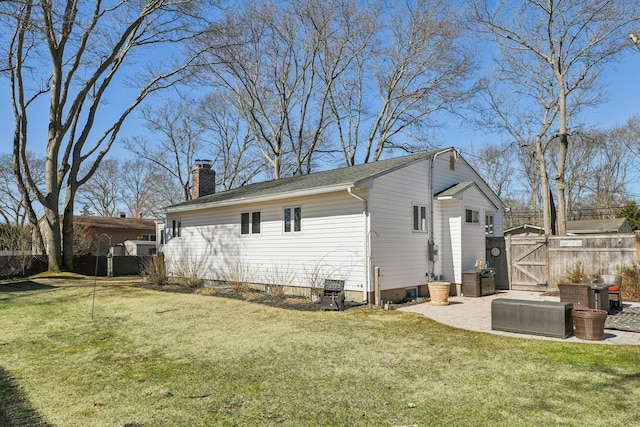 back of house with fence, a lawn, a gate, a chimney, and a patio area