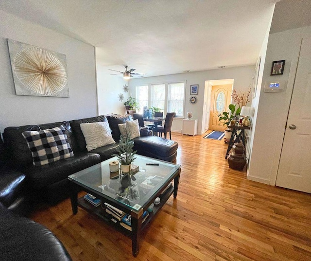 living area featuring baseboards, a ceiling fan, and light wood-style floors