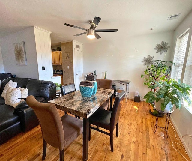 dining area with light wood-style floors, visible vents, baseboards, and a ceiling fan