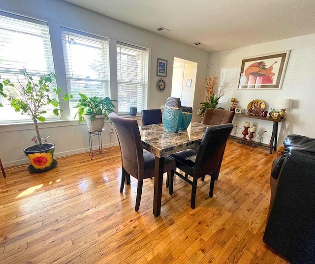 dining space with light wood finished floors, visible vents, and baseboards