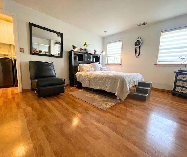 bedroom with light wood-style floors and visible vents