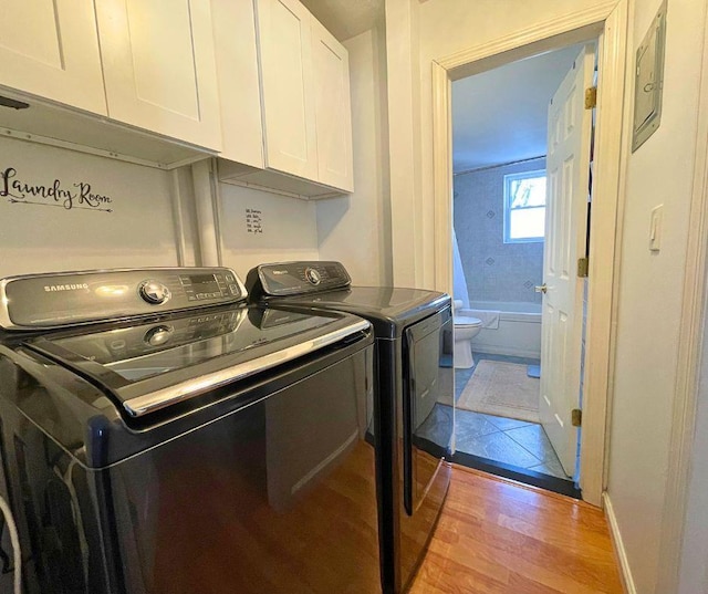 laundry area featuring baseboards, cabinet space, washing machine and clothes dryer, and wood finished floors