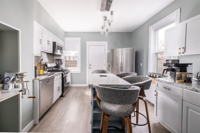 kitchen with stainless steel appliances, light wood-style floors, plenty of natural light, and decorative backsplash