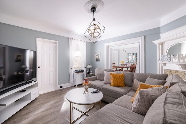 living room featuring radiator, a notable chandelier, baseboards, and wood finished floors