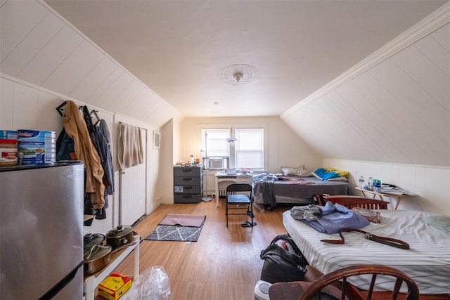 bedroom featuring light wood-style floors, freestanding refrigerator, cooling unit, and lofted ceiling