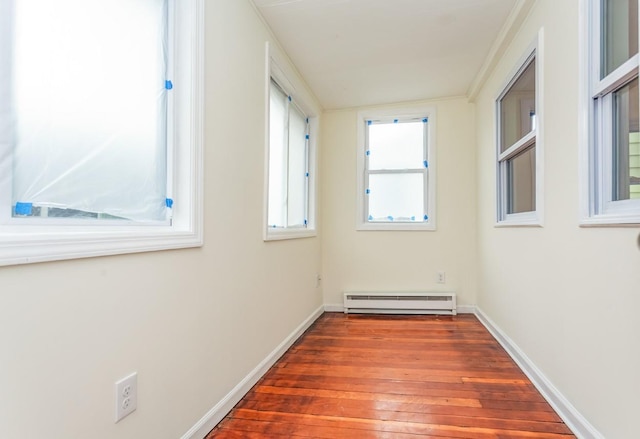 empty room featuring baseboards, baseboard heating, and hardwood / wood-style floors