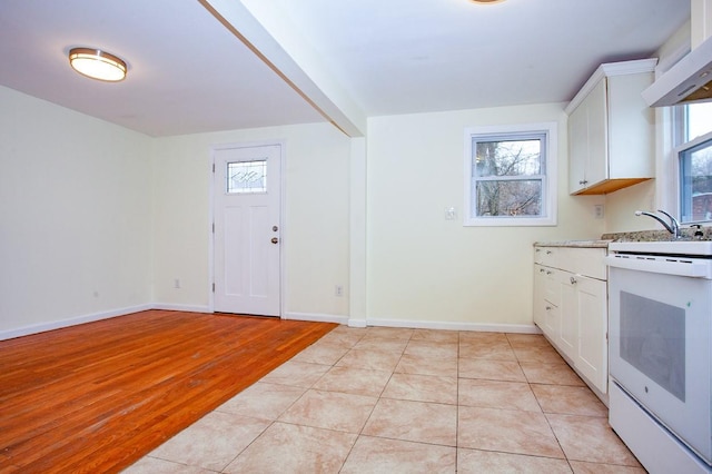 kitchen featuring white electric range oven, light tile patterned floors, baseboards, range hood, and white cabinetry