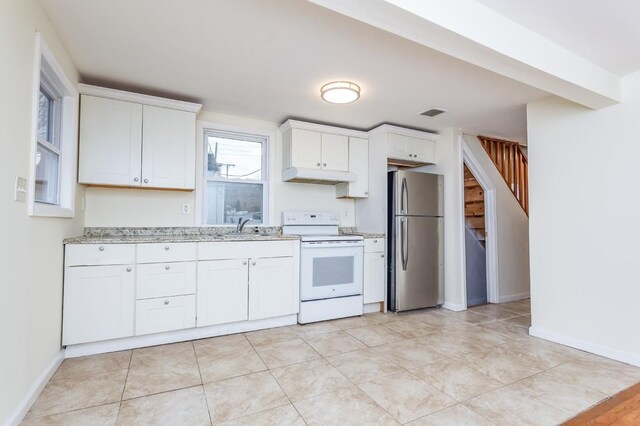 kitchen with under cabinet range hood, a sink, white cabinets, freestanding refrigerator, and white electric range oven