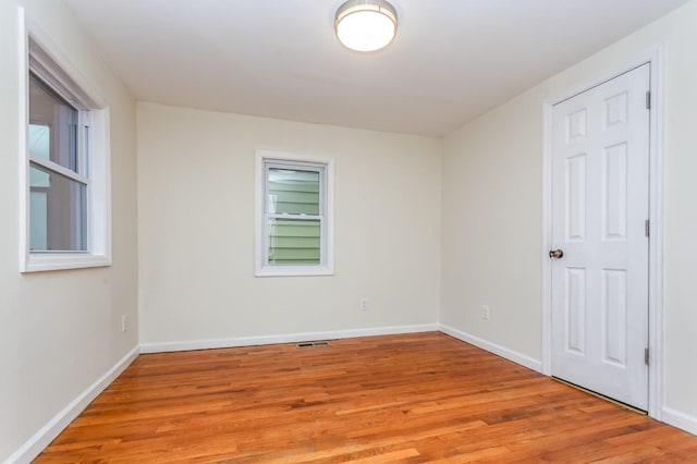 spare room with a healthy amount of sunlight, light wood-style floors, visible vents, and baseboards