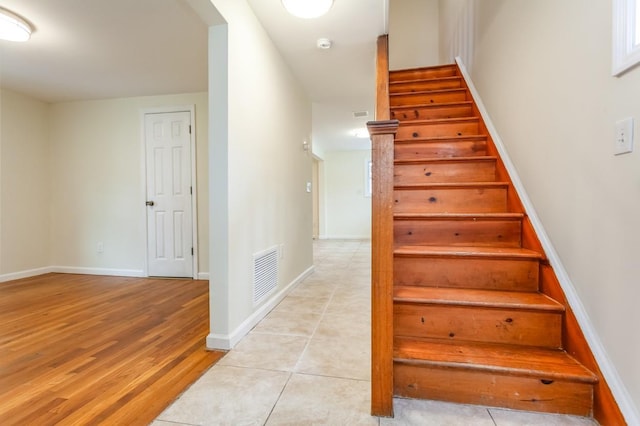 stairway with wood finished floors, visible vents, and baseboards