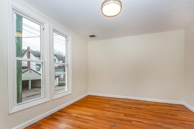 unfurnished room with light wood-type flooring, visible vents, and baseboards