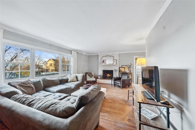 living room with ornamental molding, a large fireplace, and light wood-style flooring