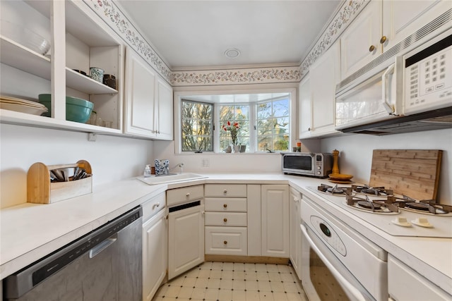 kitchen with white appliances, white cabinets, light countertops, light floors, and a sink