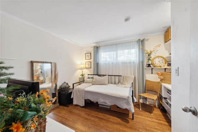 bedroom with ornamental molding and wood finished floors