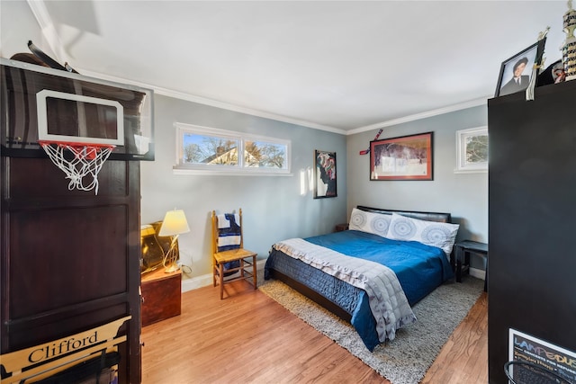 bedroom featuring light wood-style flooring, ornamental molding, and baseboards