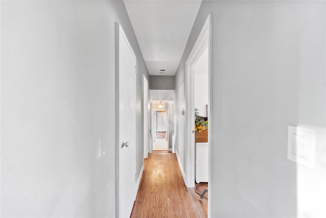 hall featuring light wood-type flooring and baseboards