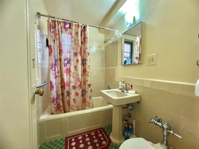 bathroom with toilet, shower / bathtub combination with curtain, tile walls, and wainscoting