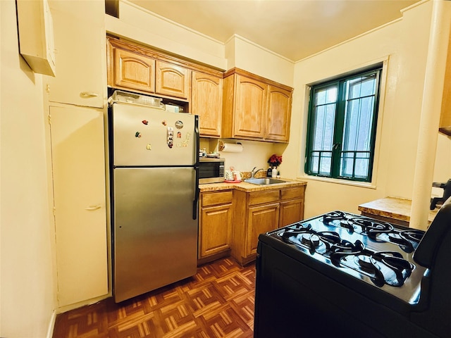 kitchen with stainless steel appliances, brown cabinetry, a sink, and light countertops