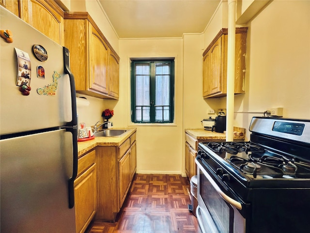 kitchen featuring stainless steel appliances, a sink, baseboards, light countertops, and brown cabinetry