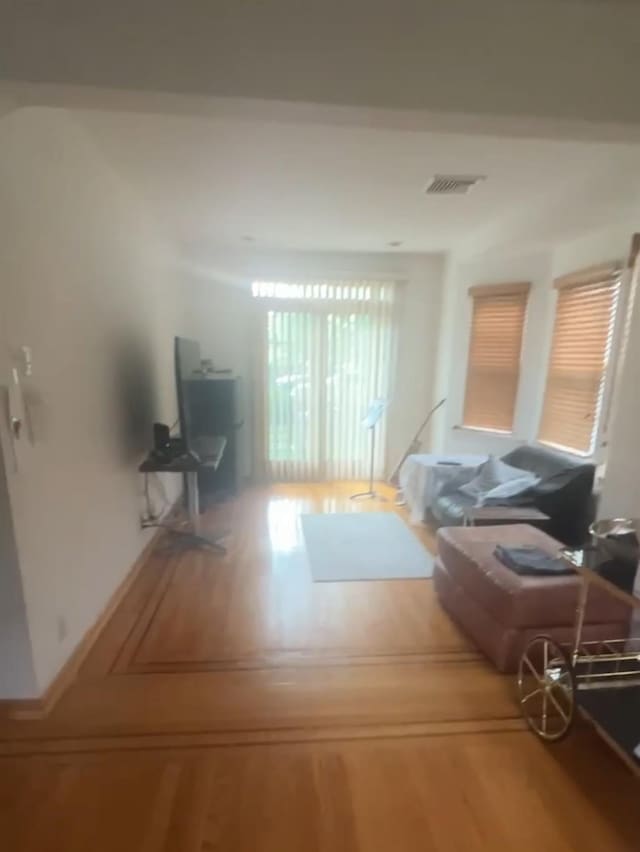 living area featuring visible vents and wood finished floors