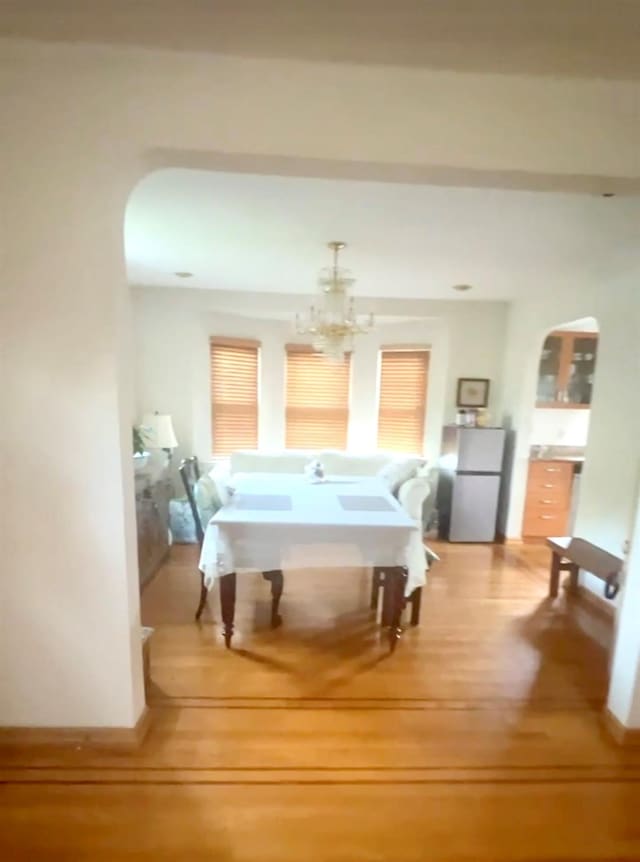 interior space featuring arched walkways, baseboards, an inviting chandelier, and wood finished floors