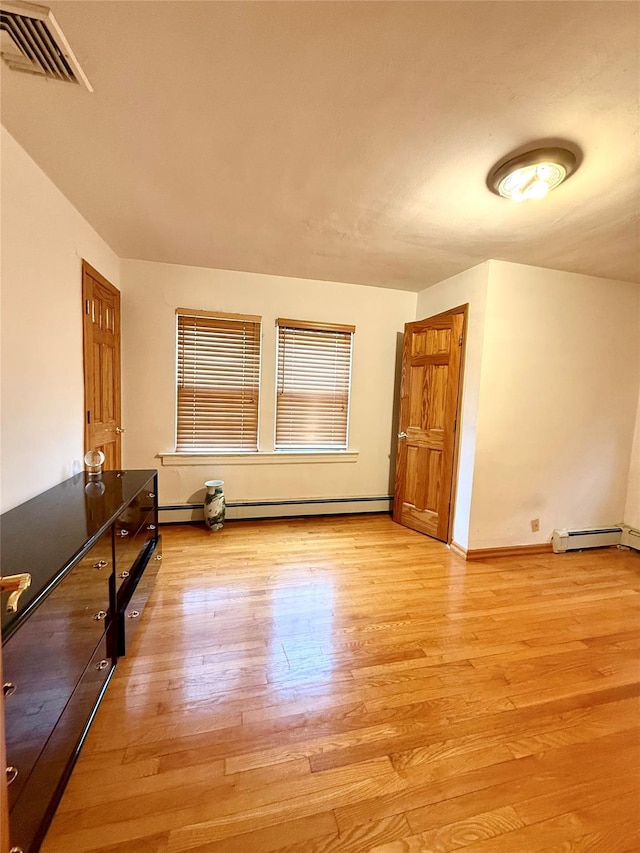 spare room with baseboards, visible vents, light wood-type flooring, and baseboard heating